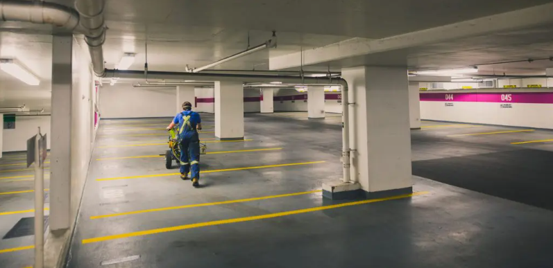 construction worker painting pavement in parking garage
